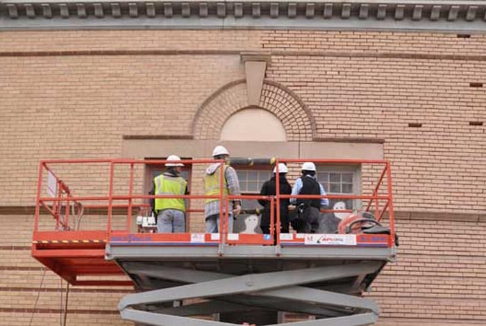 Workers on construction lift inspecting window